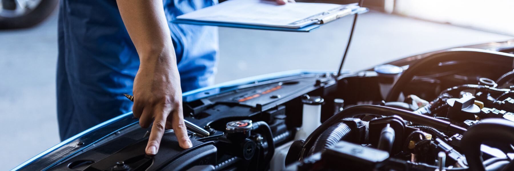 mechanic holding clipboard and looking at engine