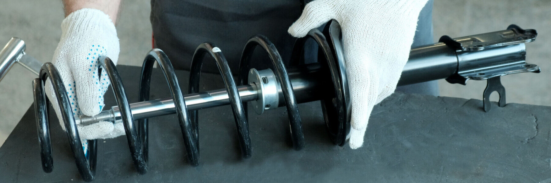 Shock absorber strut and spring in the hands of a mechanic, close-up